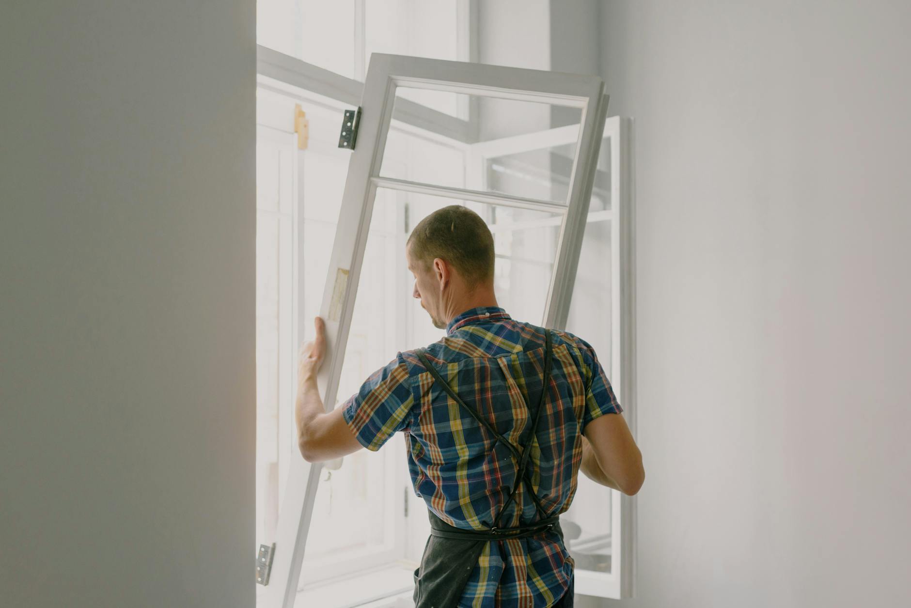 unrecognizable workman installing window in house during renovation process