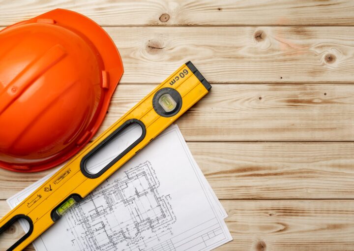 Construction worker hardhat, blueprints and .construction level, top view