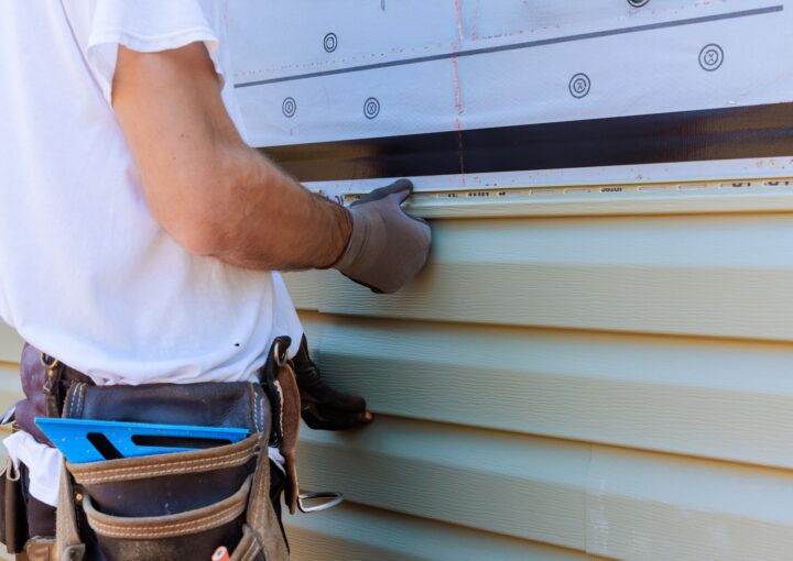 Handyman process installing vinyl PVC siding during construction on a facade new home