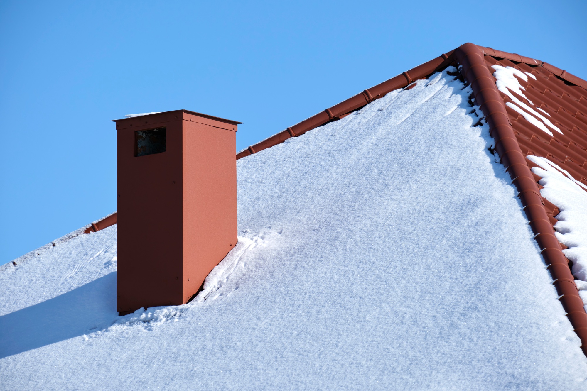 Closeup of house roof top covered with snow in cold winter.